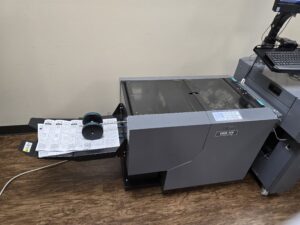 A black printer with a paper tray filled with printed sheets on a wooden table.
