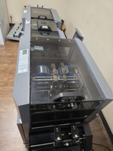 A large printer or copier machine with a transparent top cover.