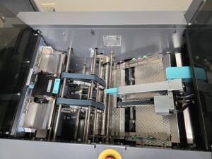 Inside view of an intricate industrial machine with metal components and blue cables.