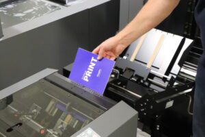 A person loading a purple booklet into a printer.