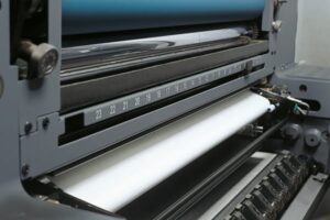 Close-up of a printing press roller with paper feed.