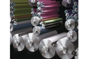 Rolls of metallic and colored foil stacked in a warehouse.