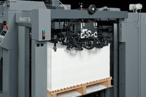 A large industrial printer printing on thick paper stacks.