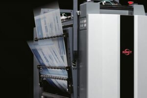 Industrial printing machine processing large sheets of paper.